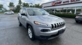 Silver Jeep SUV in the foreground of EZ Auto Sales storefront, parking lot and blue-sky clouds behind.