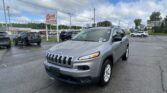 Silver Jeep SUV in a dealership lot with other cars and EZ LOAN Auto Sales sign in the background