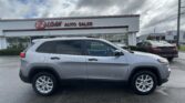 Grey SUV in the foreground at E-Z Loan Auto Sales with other cars and a Toyota dealership in the background, under a cloudy sky.