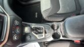 Front-center area of a Jeep interior: gear shifter, climate controls, cup holder, and passenger seat with stitching.