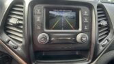 In-dash display showing the car's rearview camera with green, yellow, and red guide lines over a parking lot scene.