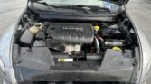 Open car hood over engine bay, showing a 2.4L MULTIAIR engine cover, battery, and fluid reservoirs in view of a parking lot.