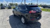 Black SUV (Jeep) seen from the rear in a parking lot under a bright blue sky with power lines above