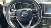 Close-up of Jeep steering wheel with dashboard gauges and touchscreen visible on the right