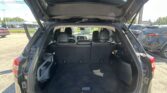 Open SUV tailgate revealing spacious black cargo area and rear seats in a parking lot.