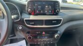Center dashboard touchscreen showing FM radio 96.9 and app icons, with climate controls below on a modern car interior