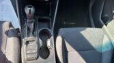 Center console of a car showing the gear shifter, cup holders, and climate control panel with various buttons and a red hazard triangle button above.