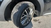 Close-up of a car wheel and tire on a gray SUV, showing the alloy wheel and tread pattern near the wheel well.
