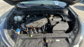 Front of a car with the hood open, showing the engine bay, battery, and coolant reservoir.