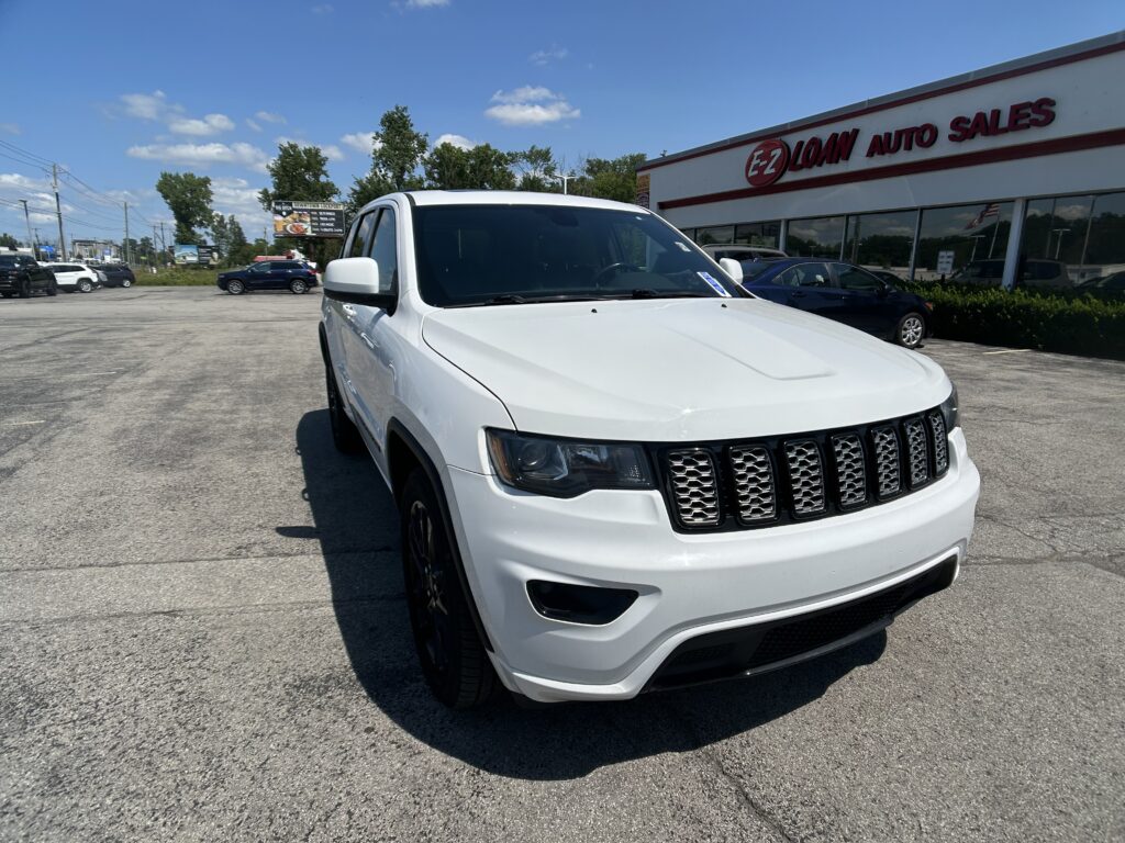 White SUV parked in a lot in front of the EZ LOAN AUTO SALES dealership sign.