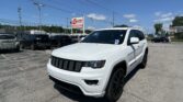 Front-right view of a white SUV in a car dealership lot with other vehicles and an EZ LOAN Auto Sales sign in the background on a sunny day.
