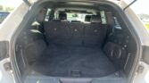 SUV rear hatch open showing spacious cargo area with upright third-row seats and black interior carpeting