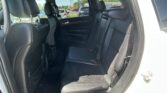 Rear interior of a black leather SUV with two rows of seats and headrests, showing the door panel and seat belts in the back seat area.