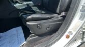 Front interior of a car showing black leather seats, center console with gear shifter, and an open door frame with a sticker on the edge.