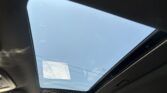 Blue sky visible through a panoramic sunroof, with dark car interior framing the glass roof