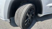 Front wheel and tire visible inside the vehicle's front fender well of a light-colored SUV.