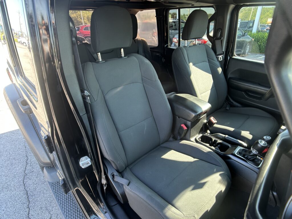 Interior of a dark fabric SUV showing front seats, center console, and door frame with sunlight entering from open door