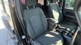 Interior of a dark fabric SUV showing front seats, center console, and door frame with sunlight entering from open door