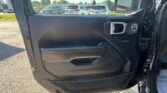 Inside view of a car door panel with a side mirror, overlooking a parking lot full of white and silver cars outside nearby.