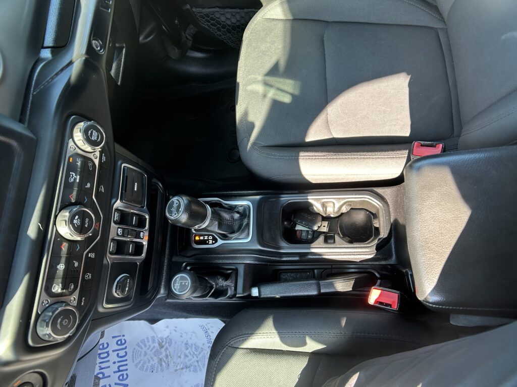Interior view of a car cockpit showing the center console with gear shifter, climate controls, and steering wheel nearby.