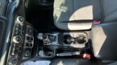 Interior view of a car cockpit showing the center console with gear shifter, climate controls, and steering wheel nearby.
