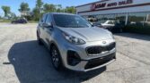 Silver Kia SUV in the foreground at a car dealership lot with EZ Loan Auto Sales building in the background