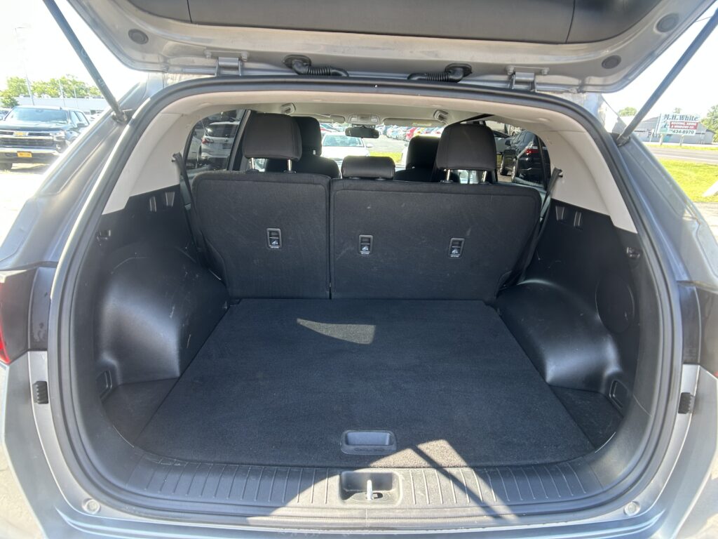 Open SUV trunk with rear seats upright and spacious cargo area visible in a dealership parking lot.