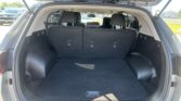 Open SUV trunk with rear seats upright and spacious cargo area visible in a dealership parking lot.