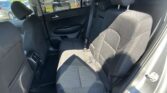 Back seat area of a car with dark fabric upholstery, headrests, and visible seat belts, parking lot seen through the window.