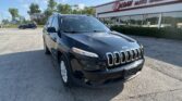Black Jeep SUV parked in front of EZ Loan Auto Sales on a sunny day, with the dealership sign visible in the background.