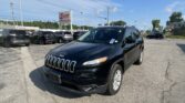 Black Jeep SUV in foreground at a daytime car dealership lot with other vehicles and an EZ Loan Auto Sales sign nearby