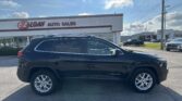 Black Jeep Cherokee parked in front of E-Z Loan Auto Sales on a sunny day.