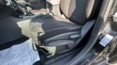 Interior of a car showing the front passenger seat and center console with gear shifter, handbrake, and cup holder; a paper floor mat lies on the floor near the door.