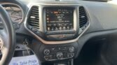 Inside a car cockpit with the center touchscreen displaying FM radio 93.7 Rhythm & Blues and a parking lot visible through the windshield