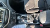Interior of a car focusing on the center console with gear shifter, cup holders, and driver-side controls visible on the left edge.