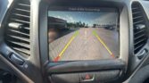 Rearview camera display showing guide lines as the car reverses, with a warning to check surroundings.