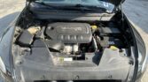 Open car hood showing the engine bay with a prominent black engine cover labeled "MULTIAIR 2.4L" and surrounding components like the coolant reservoir and battery on the right side.