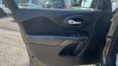 Inside car door panel with window controls, view of parking lot and other vehicles outside the open door side mirror visible