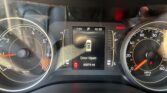 Car dashboard view: tachometer on left, speedometer on right, central display shows 73°F, gear P, time 10:33, and 'Door Open' message with odometer reading 82,574 miles. Red BRAKE indicator lit.