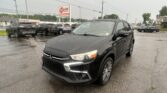 Black SUV in the foreground at a rainy car dealership lot with an EZ Loan Auto Sales sign in the background.