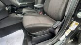 Front cabin of a car with black seats featuring red stitching, center console, and gear shifter visible by the driver door.