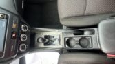Interior of a car showing the center console, gear shifter, climate controls, and red-stitch cloth seats on the passenger side.