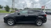 Black SUV in a car dealership lot with EZ Loan Auto Sales sign and an American flag on a cloudy day.