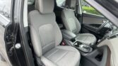 Open-door view of a gray-car interior with two front seats, center console, and steering wheel on the right, in a parking lot.