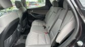 Rear passenger seating area of a gray SUV with three-seat bench, visible seat belts, and door panel trim.