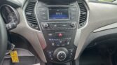 Center dashboard with touchscreen radio showing 103.3 FM, surrounded by buttons and two air vents on a dark gray car interior; a yellow key tag hangs near the ignition on the left.