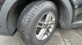 Wheel and tire mounted on a vehicle, showing tread pattern and alloy rim inside the wheel well