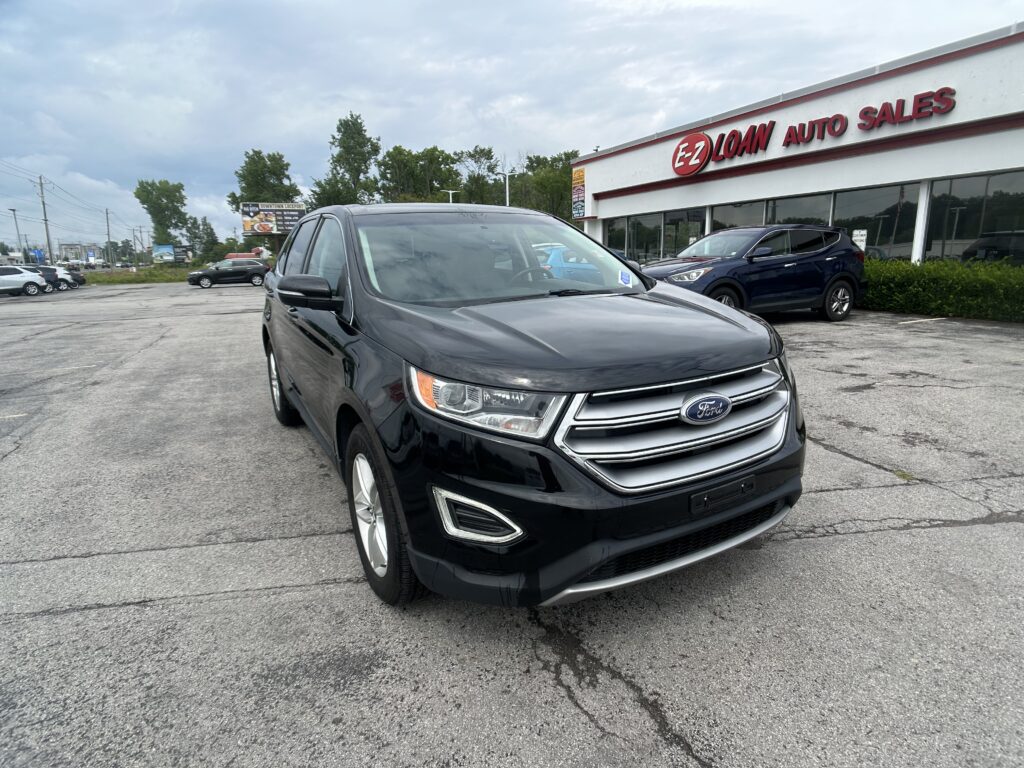 Front of a black Ford SUV parked in a dealership lot with EZ Loan Auto Sales building in the background, cloudy sky above.