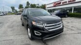 Front of a black Ford SUV parked in a dealership lot with EZ Loan Auto Sales building in the background, cloudy sky above.