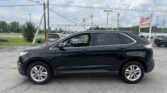 Black SUV parked in a lot with a leaning utility pole and EZ Auto Sales sign in the background under a cloudy sky.